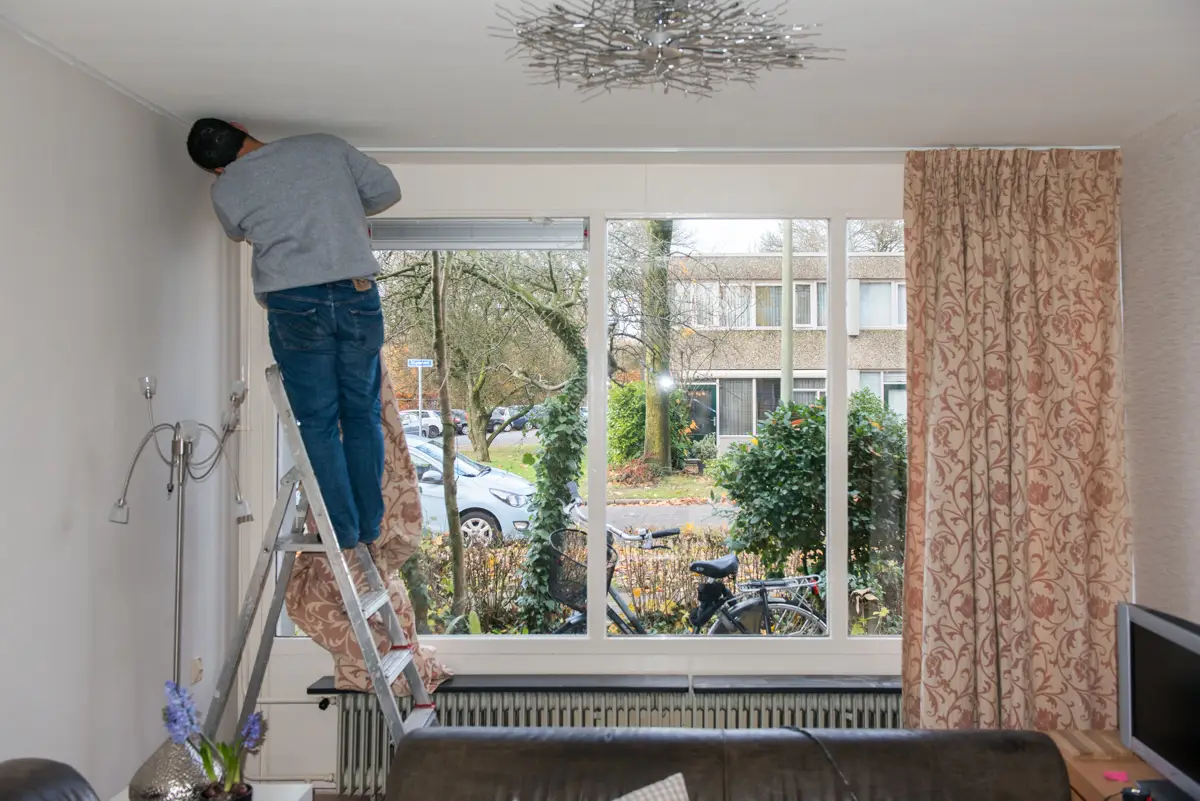 omar hangt gordijnen in zijn nieuwe huis