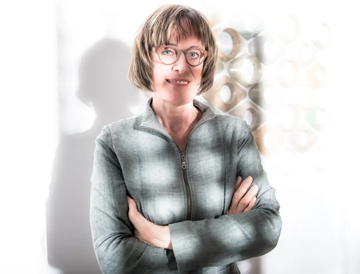 christine staat naast haar kunstwerk in de schaduw van een ander kunstwerk.