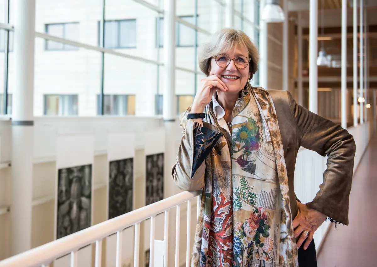 vrouw staat tegen een leuning voor het raam.